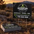 Custom printed coroplast yard sign and a stack of matching signs for 'Recognition Branded Gear' displayed outdoors in a grassy field at sunset, with mountains in the background.