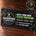 A black custom printed banner with metal grommets displayed on a dark wood surface, featuring a gear logo and text for 'Recognition Branded Gear' plus a circular inset showing the hems and grommets.