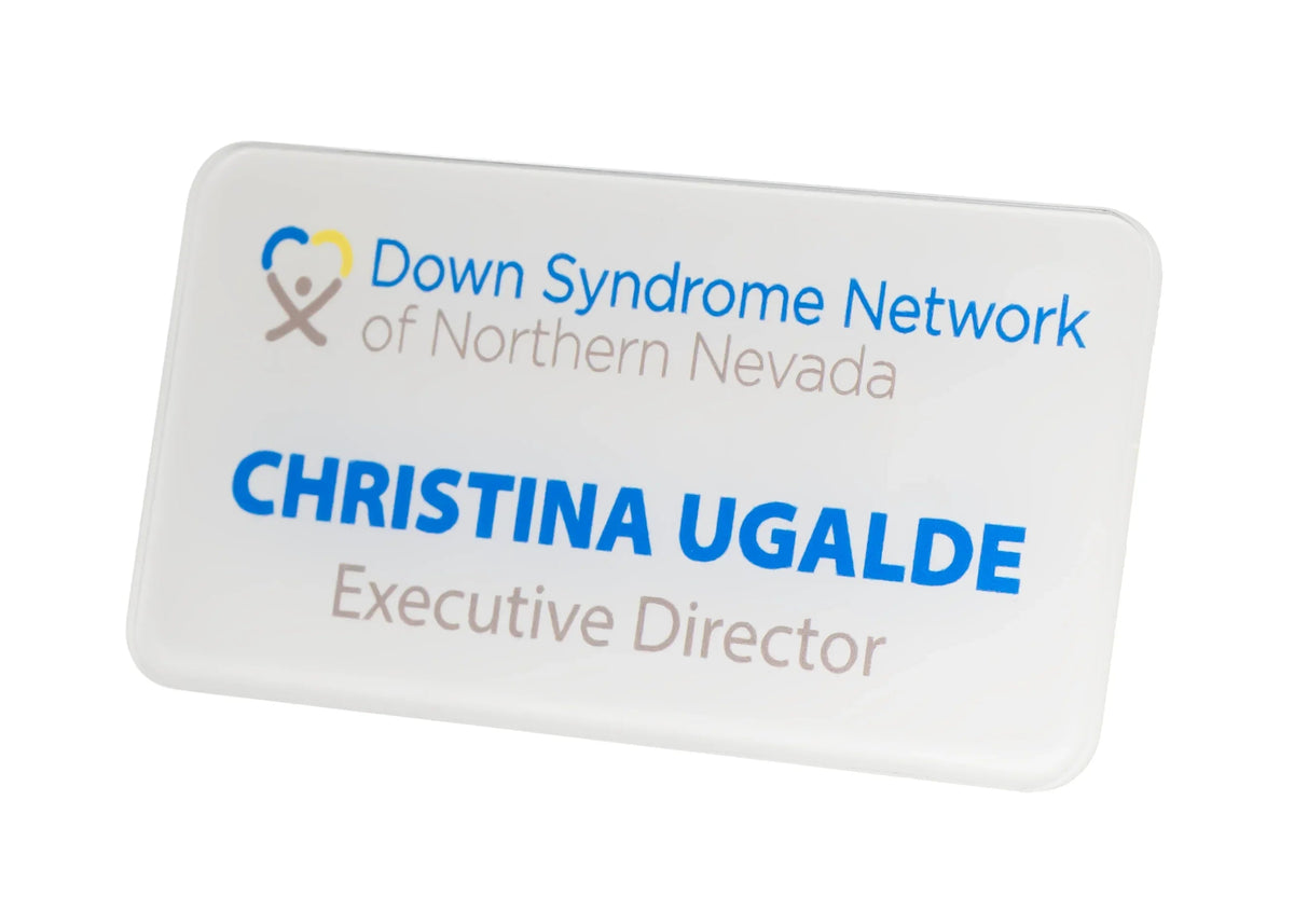 A white rectangular name badge with rounded corners, featuring the Down Syndrome Network of Northern Nevada logo in blue and gray lettering.