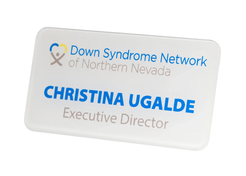A white rectangular name badge with rounded corners, featuring the Down Syndrome Network of Northern Nevada logo in blue and gray lettering.