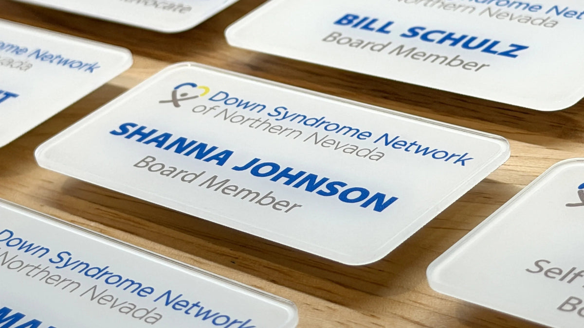 Close-up of name badges with 'Down Syndrome Network of Northern Nevada' on a wooden surface.