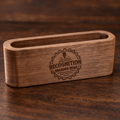 A rectangular wooden business card holder with rounded corners and an open top, featuring a laser-engraved circular logo that reads 'RECOGNITION BRANDED GEAR' with a gear and laser icon. The item is shown on a dark wood surface.