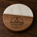 A round wooden and white marble like epoxy coaster on a dark wood tabletop, featuring a laser-engraved logo that reads 'RECOGNITION BRANDED GEAR'.