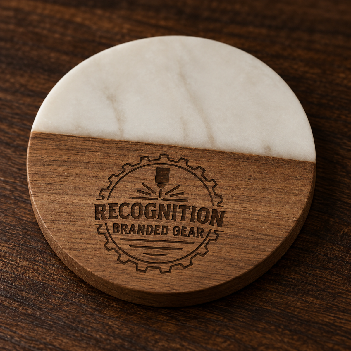 A round wooden and white marble like epoxy coaster on a dark wood tabletop, featuring a laser-engraved logo that reads 'RECOGNITION BRANDED GEAR'.