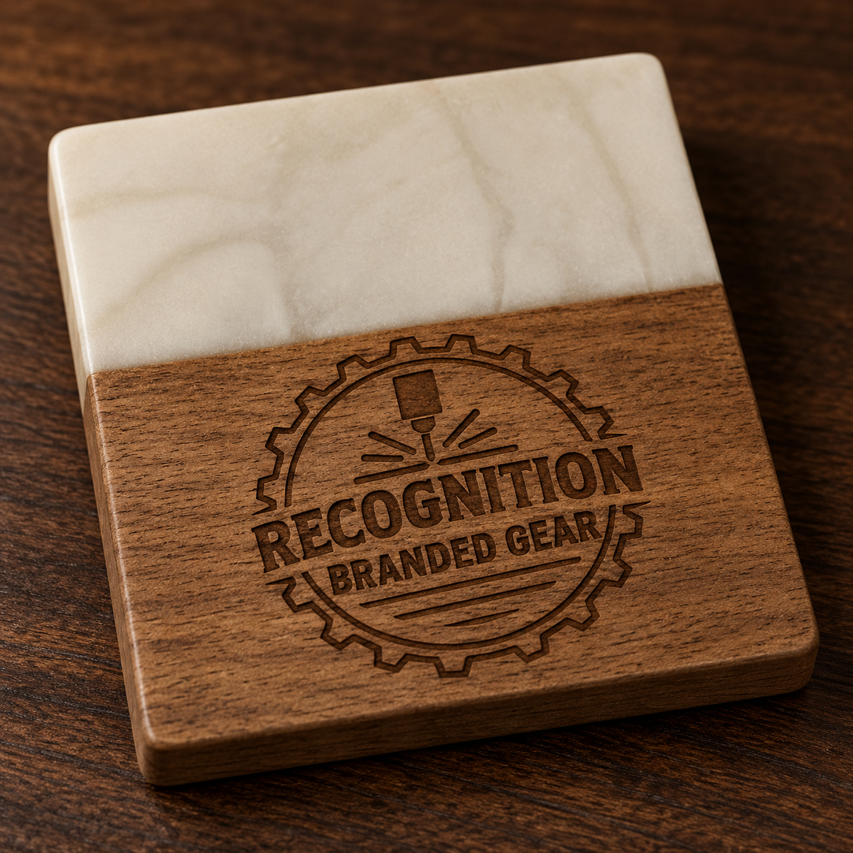 A square wooden coaster with a white marble like epoxy top half and a brown wood bottom half, featuring an engraved circular logo that reads 'RECOGNITION BRANDED GEAR' on a dark wood surface.