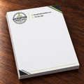 A stack of white branded letterhead on a dark wood tabletop. The top page shows the Recognition Branded Gear logo and contact details in black and lime green, with dark gray corner accents.